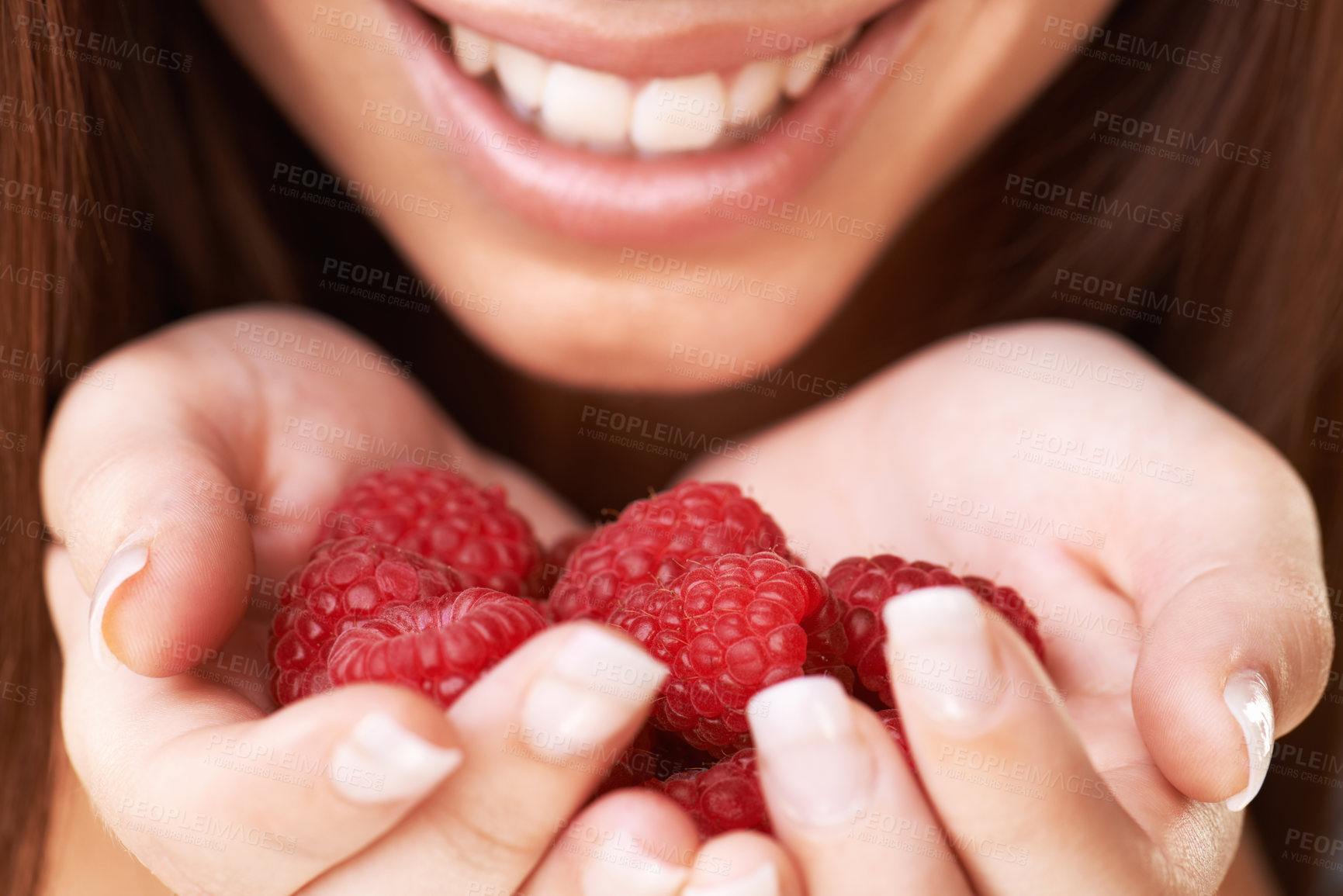 Buy stock photo Cropped image of a happy young woman holding a bunch of raspberries