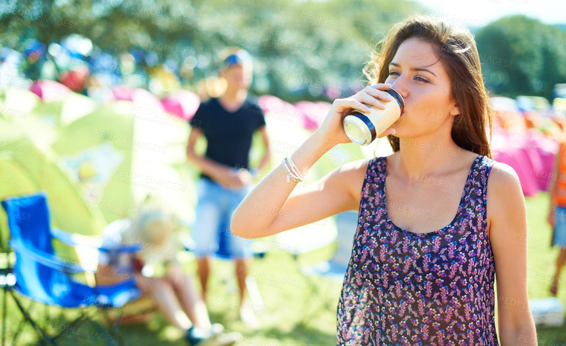 Buy stock photo Shot of a young woman drinking a can of beer at an outdoor festival