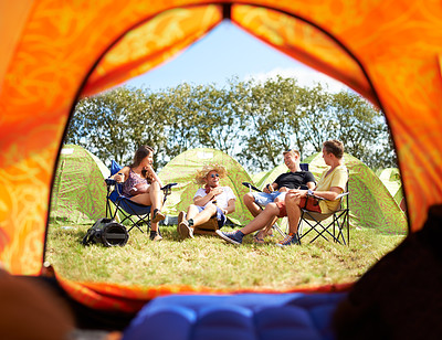 Buy stock photo Shot of a group of friends sitting outside their tent at a festival