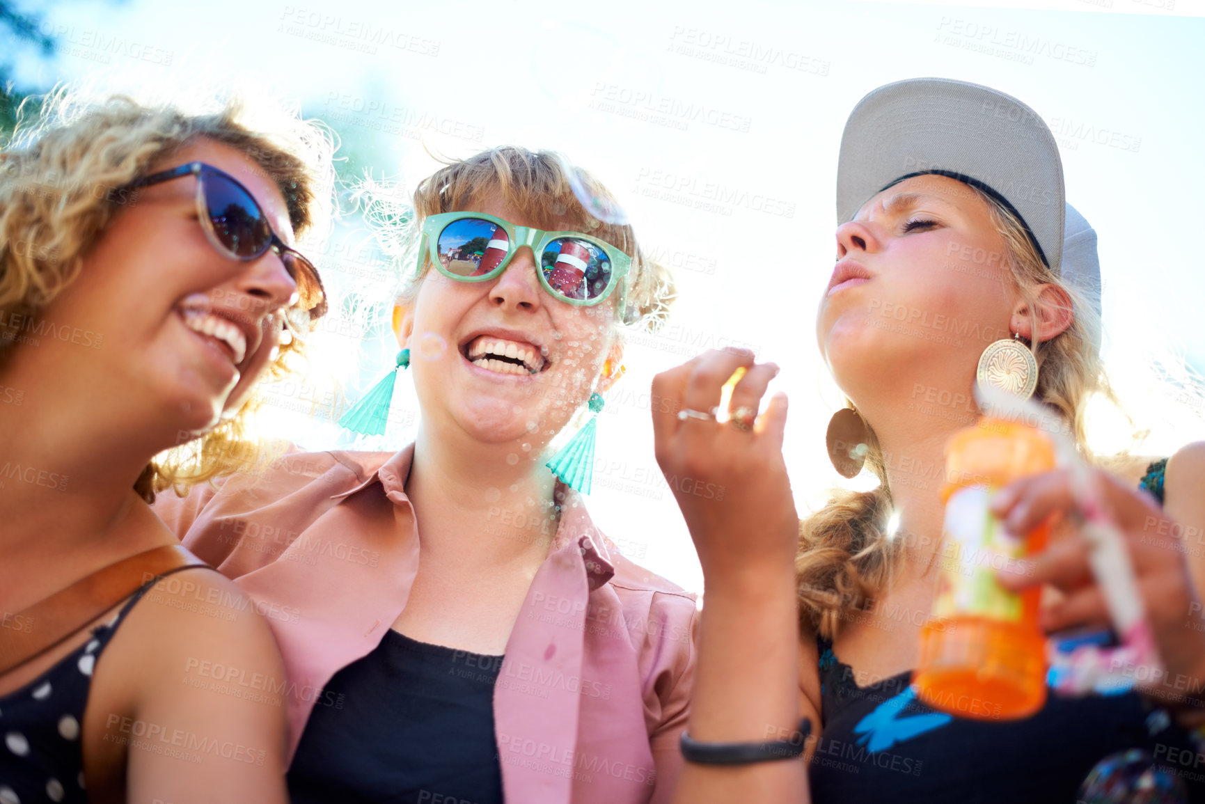 Buy stock photo Blowing bubbles, women and outdoor with friends, happiness and sunshine with fun, playing and bonding together. People, festival and group with carefree, excited and celebration with weekend break