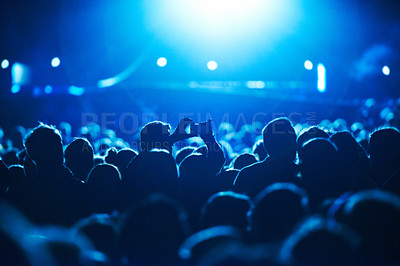 Buy stock photo People, blue and crowd for concert, performance or stage in arena for rock, psychedelic or electric music. Lens flare, light and equipment with person, holding and smartphone for social media post