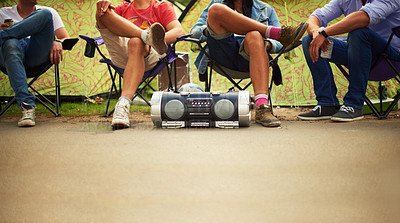 Buy stock photo Four friends enjoying music from a stereo while sitting in camping chairs at a music fest