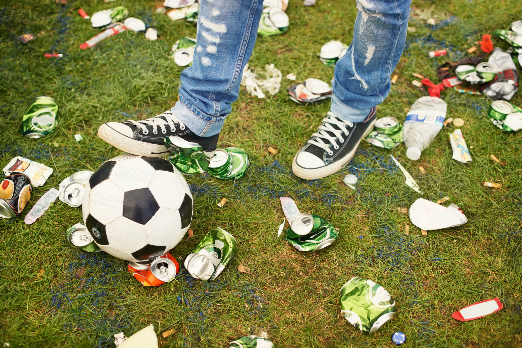 Buy stock photo A person playing with a football amidst the trash left behind at a music festival