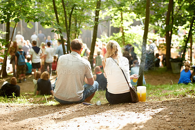 Buy stock photo Rearview shot of a couple sitting amongst the trees at an outdoor event