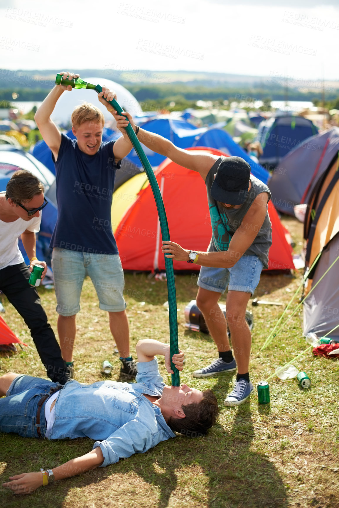 Buy stock photo Man, friends and beer pipe at outdoor festival, camp or party together with alcohol on green grass or field. Group of people pouring drink down tube in nature by tents at event or carnival outside