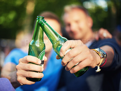 Buy stock photo Closeup image of two guys toasting their beer bottles at a music festival