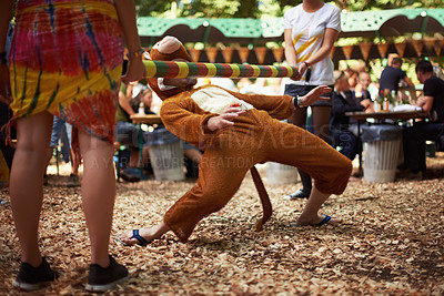 Buy stock photo A guy dressed in a monkey costume doing the limbo dance at a music festival