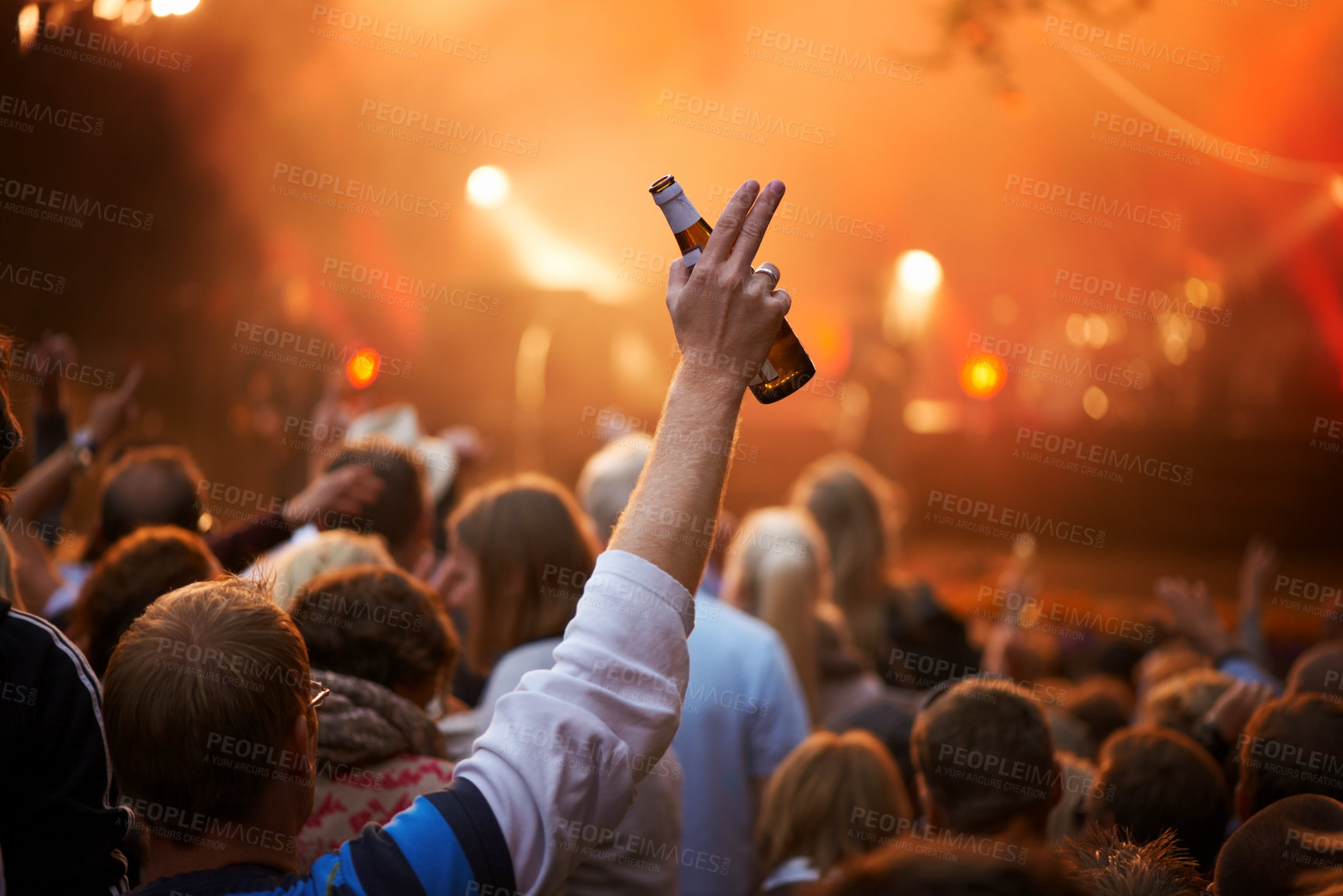 Buy stock photo Rear view of a guy in an audience saluting the band on stage at a music festival