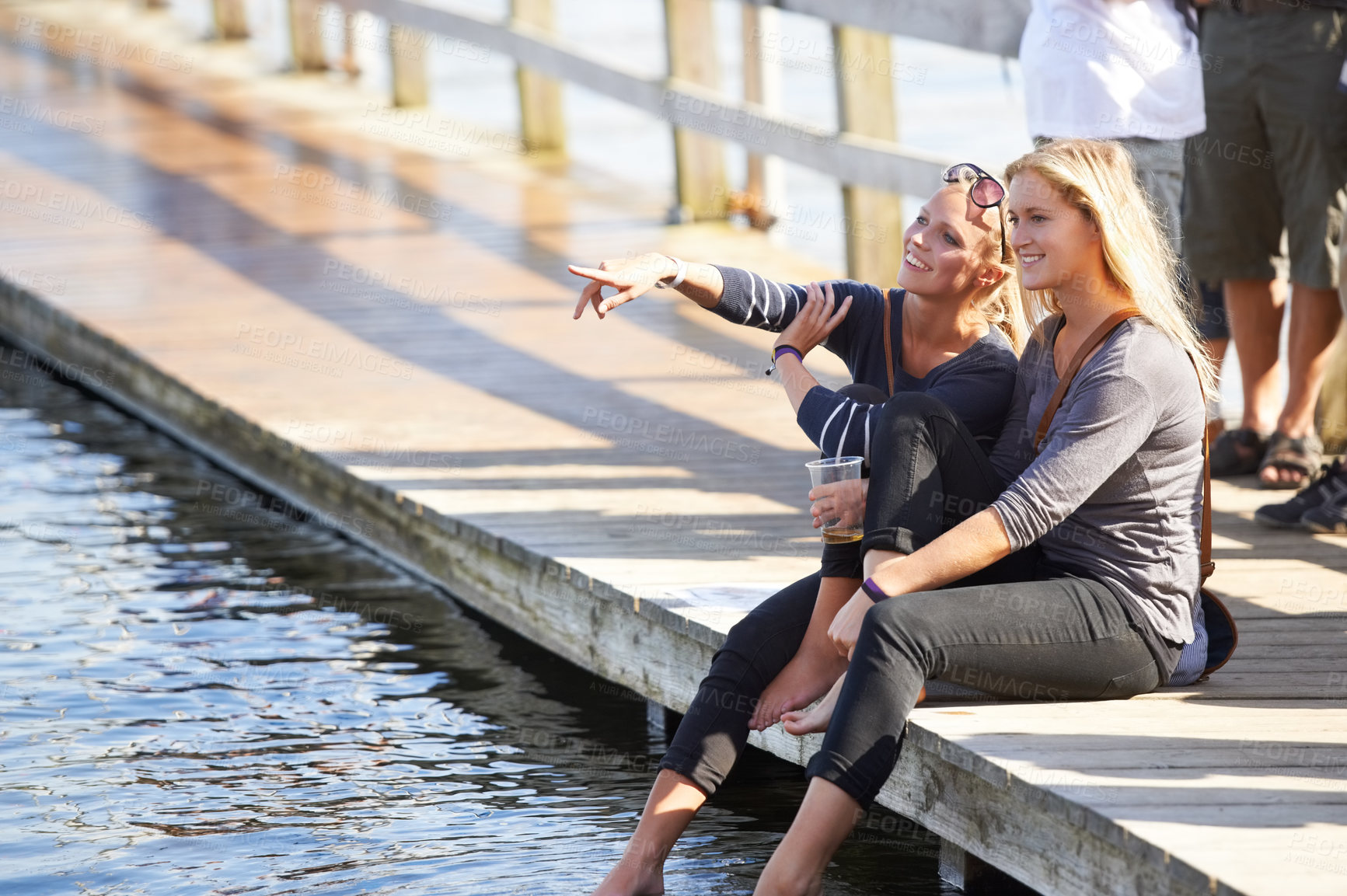 Buy stock photo People, drink and holiday at lake with beer, water or deck in summer with women pointing to view. Friends, party and relax at dam with alcohol, chat and fun at social, event or sitting on pier