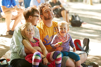 Buy stock photo A young family of four sitting down to enjoy the bands at an outdoors music festival