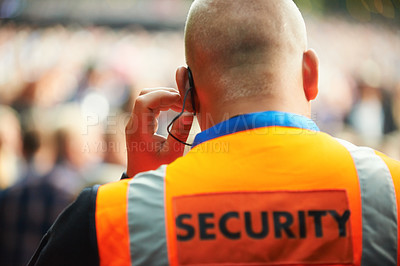 Buy stock photo Rear view of a security guard listening to his headset
