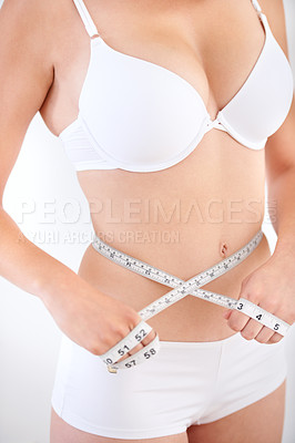Buy stock photo A young woman in her underwear with a measuring tape wrapped around her stomach