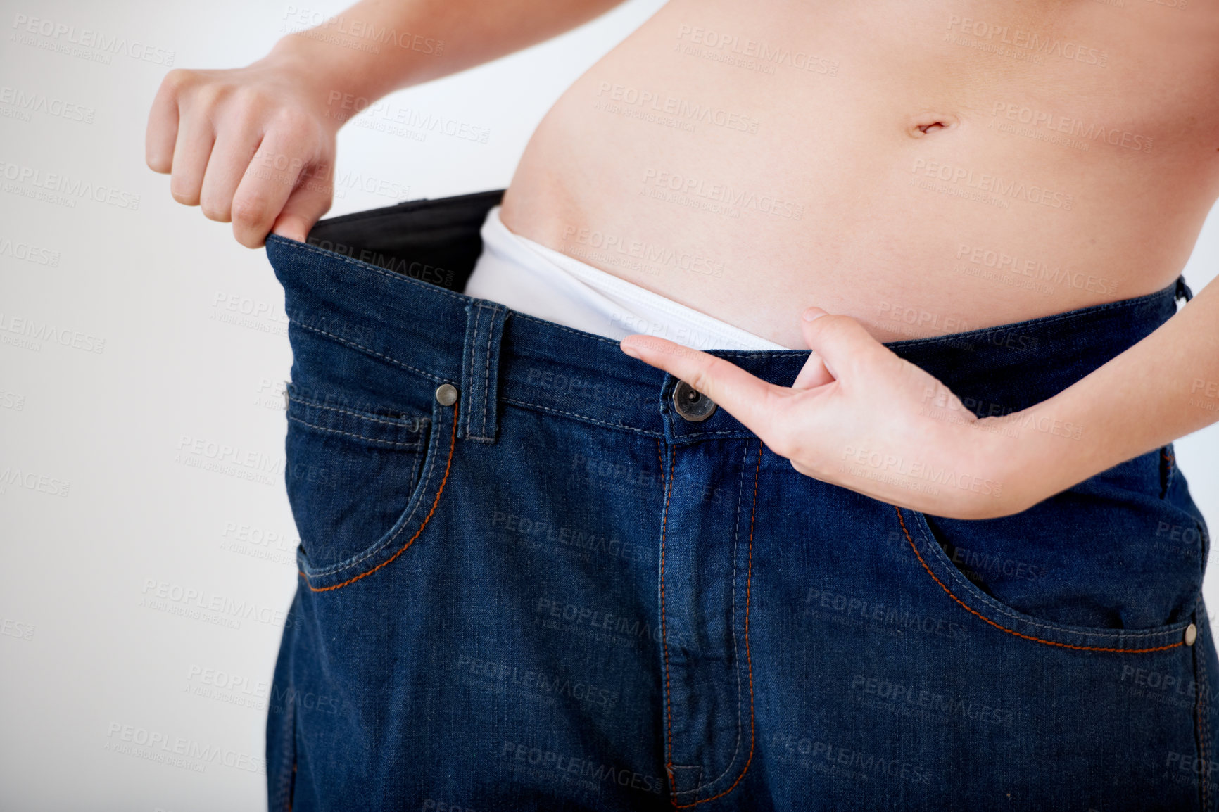 Buy stock photo Cropped image of a woman pulling the waistband of her pants - Weight Loss
