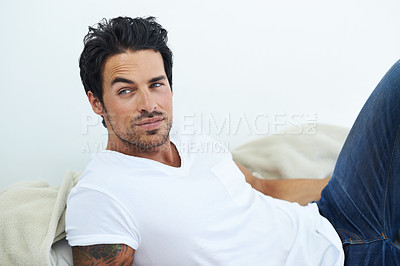 Buy stock photo Shot of ruggedly handsome man wearing a white t-shirt and lying on a bed