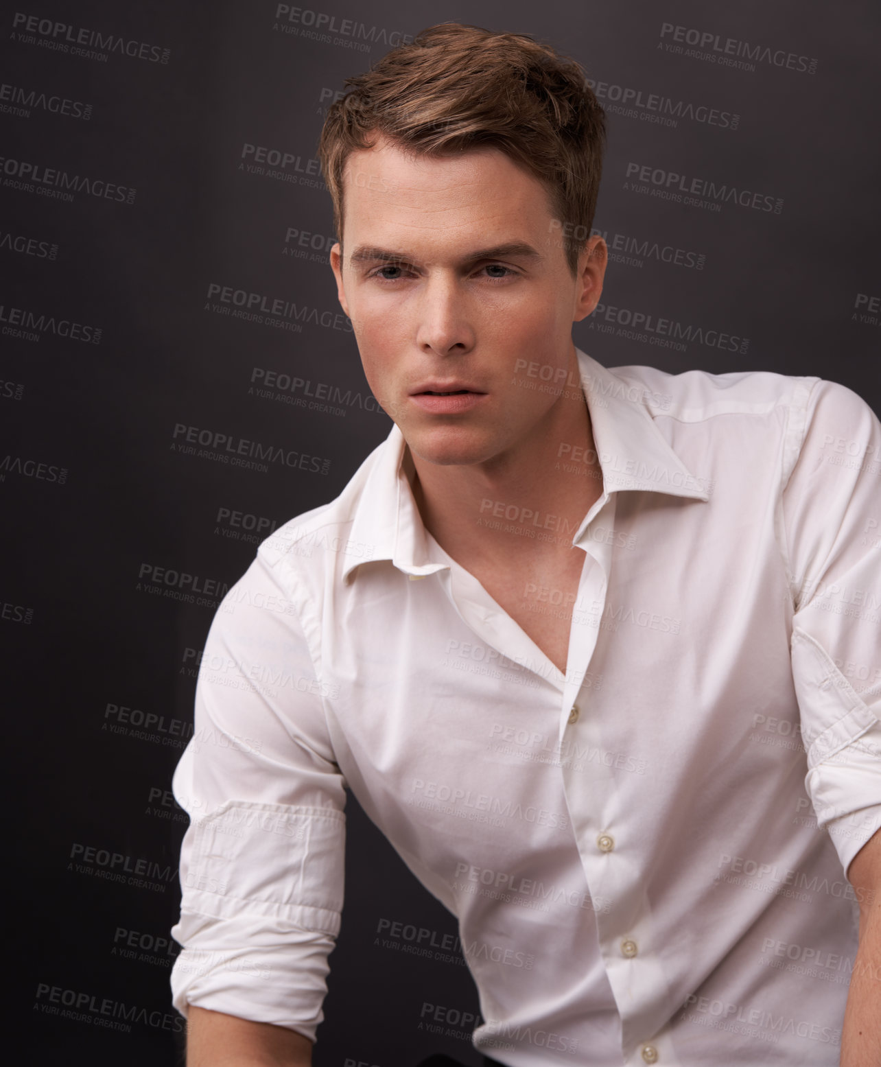 Buy stock photo A handsome young man in a white shirt against a black background