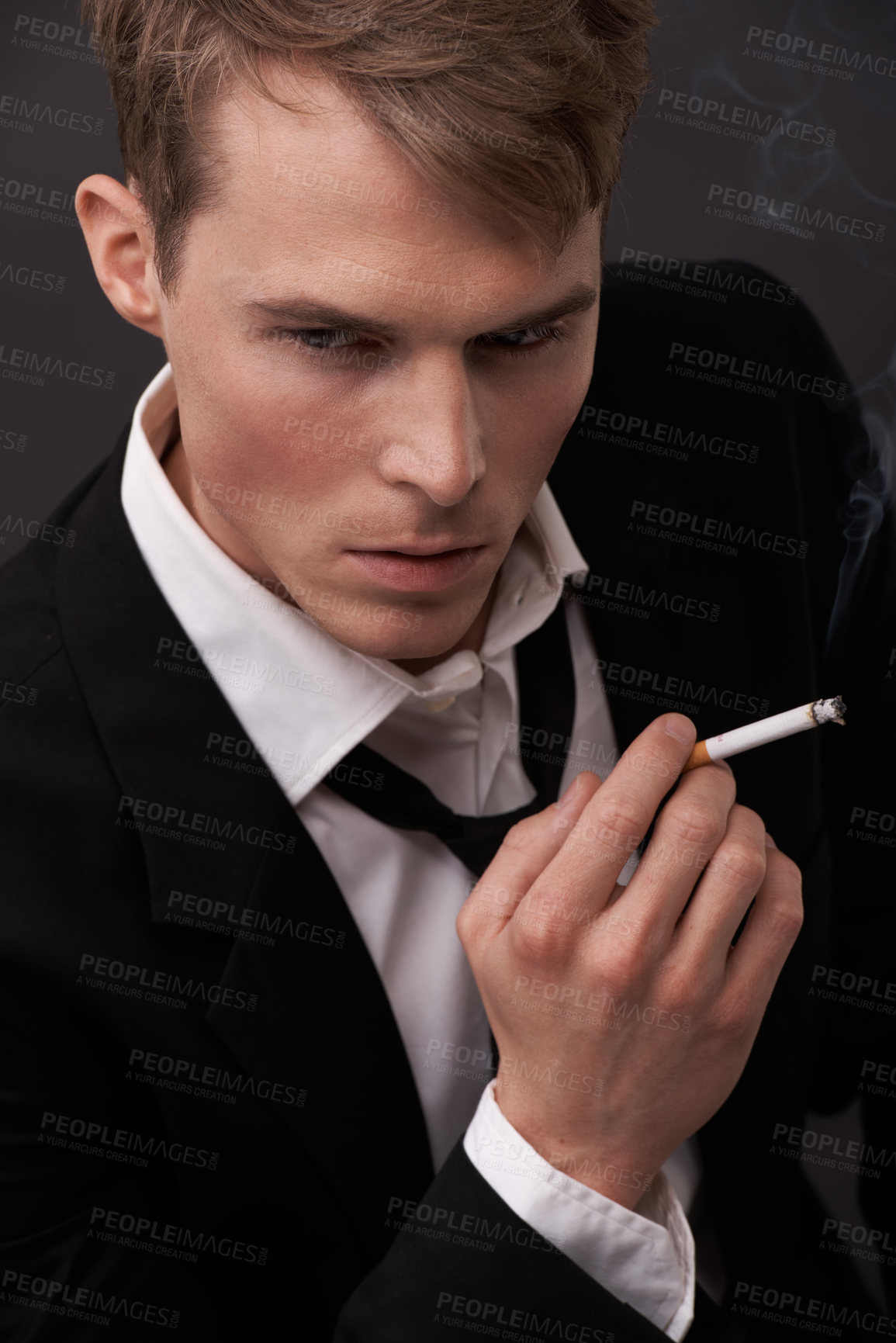 Buy stock photo Face, thinking and a man smoking a cigarette in studio on a dark background for tobacco addiction. Nicotine, habit and unhealthy with a young person in a suit, taking a break from business to smoke