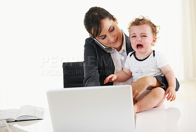 Buy stock photo Working mom talking on the phone while holding a crying baby