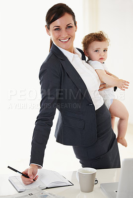 Buy stock photo Working mother holding her baby while smiling and signing a document