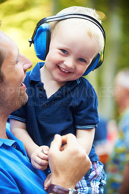 Buy stock photo Cute little boy lifted up by his father while wearing noise-canceling headphones