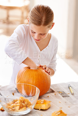 Buy stock photo A little girl hollowing out a pumpkin at home for halloween