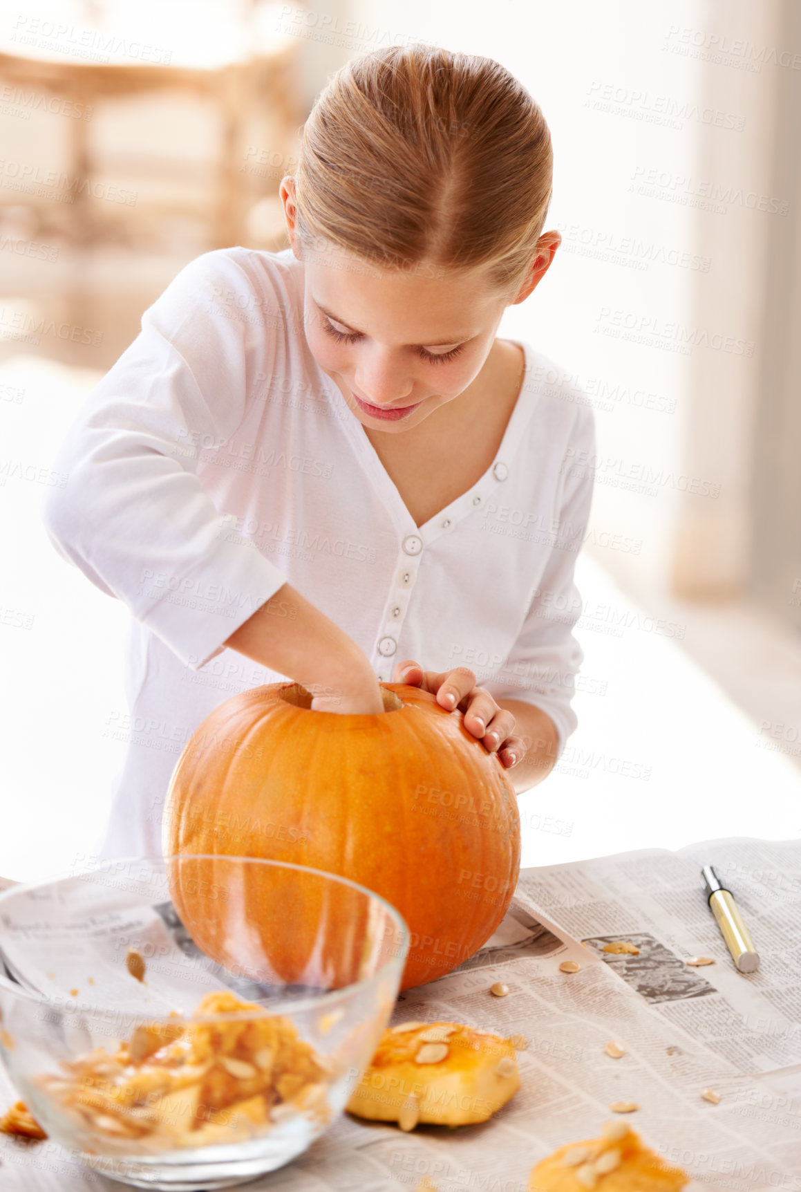 Buy stock photo A little girl hollowing out a pumpkin at home for halloween