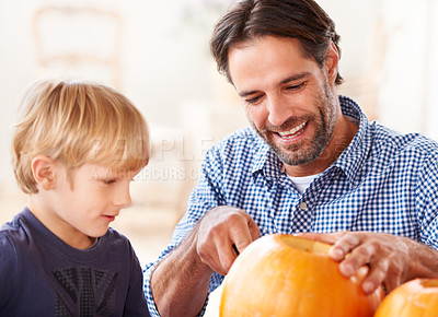Buy stock photo A father and son bonding while carving a pumpkins for halloween