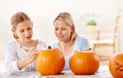 Buy stock photo Shot of a mother and daughter carving a pumpkin together