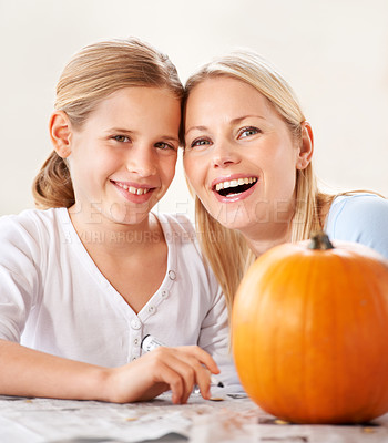Buy stock photo Shot of a mother and daughter carving a pumpkin together