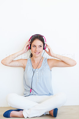 Buy stock photo Music, thinking and woman on a floor with headphones in studio, happy and streaming on a wall background. Contemplation, smile and girl relax for podcast, radio or audio track while sitting on mockup