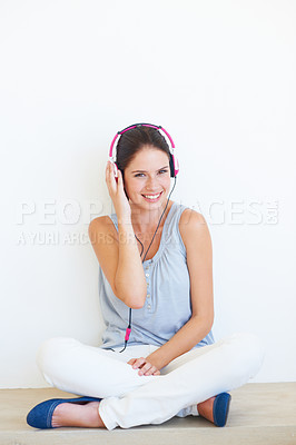 Buy stock photo Woman, music and portrait with headphones on a floor in studio, happy and streaming on a wall background. Face, smile and girl relax with podcast, radio or audio track while sitting against mockup