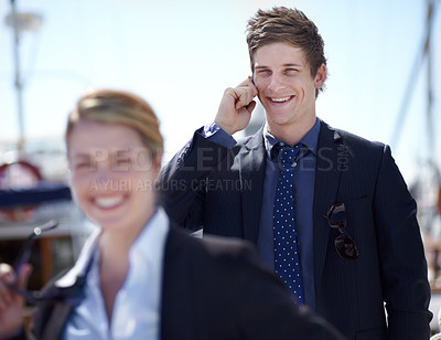 Buy stock photo Young businessman on his mobile with a coworker in front of him while outdoors