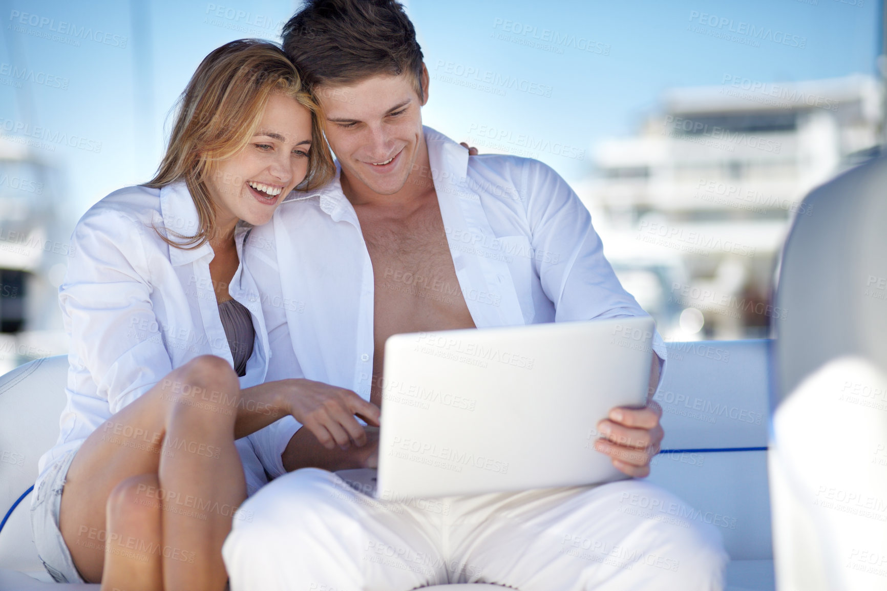 Buy stock photo Young couple using a laptop together on a yacht