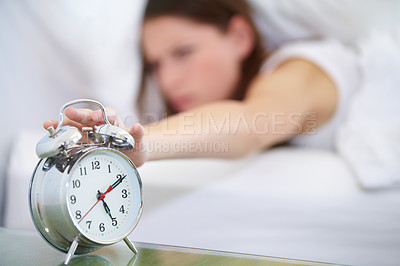 Buy stock photo A young woman pressing the stop button on her alarm clock