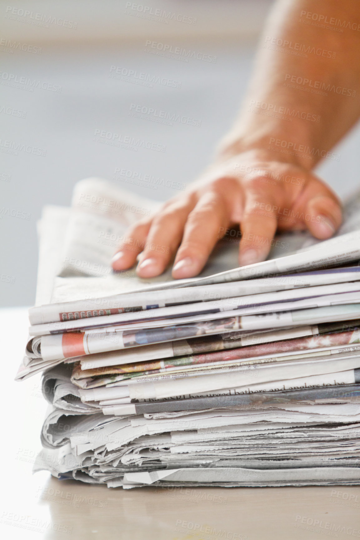 Buy stock photo Shot of a hand on top of a stack of newspapers