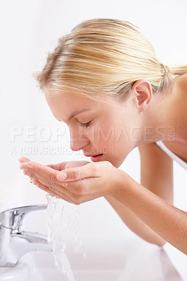 Buy stock photo Shot of an attractive young woman washing her face with water over a sink