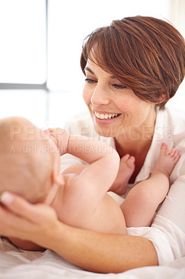 Buy stock photo Mother, baby and happiness or love, play and relaxing on bed, bonding and joy in parenthood. Mom, newborn and peace or calm at home, positive and happy for child development, smile and fun together