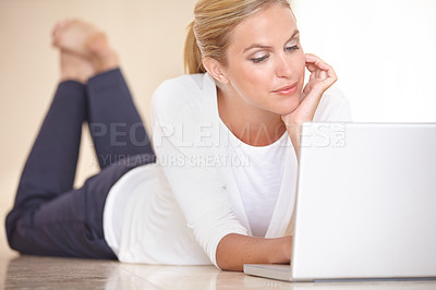 Buy stock photo A gorgeous young woman lying on the floor while working on her laptop