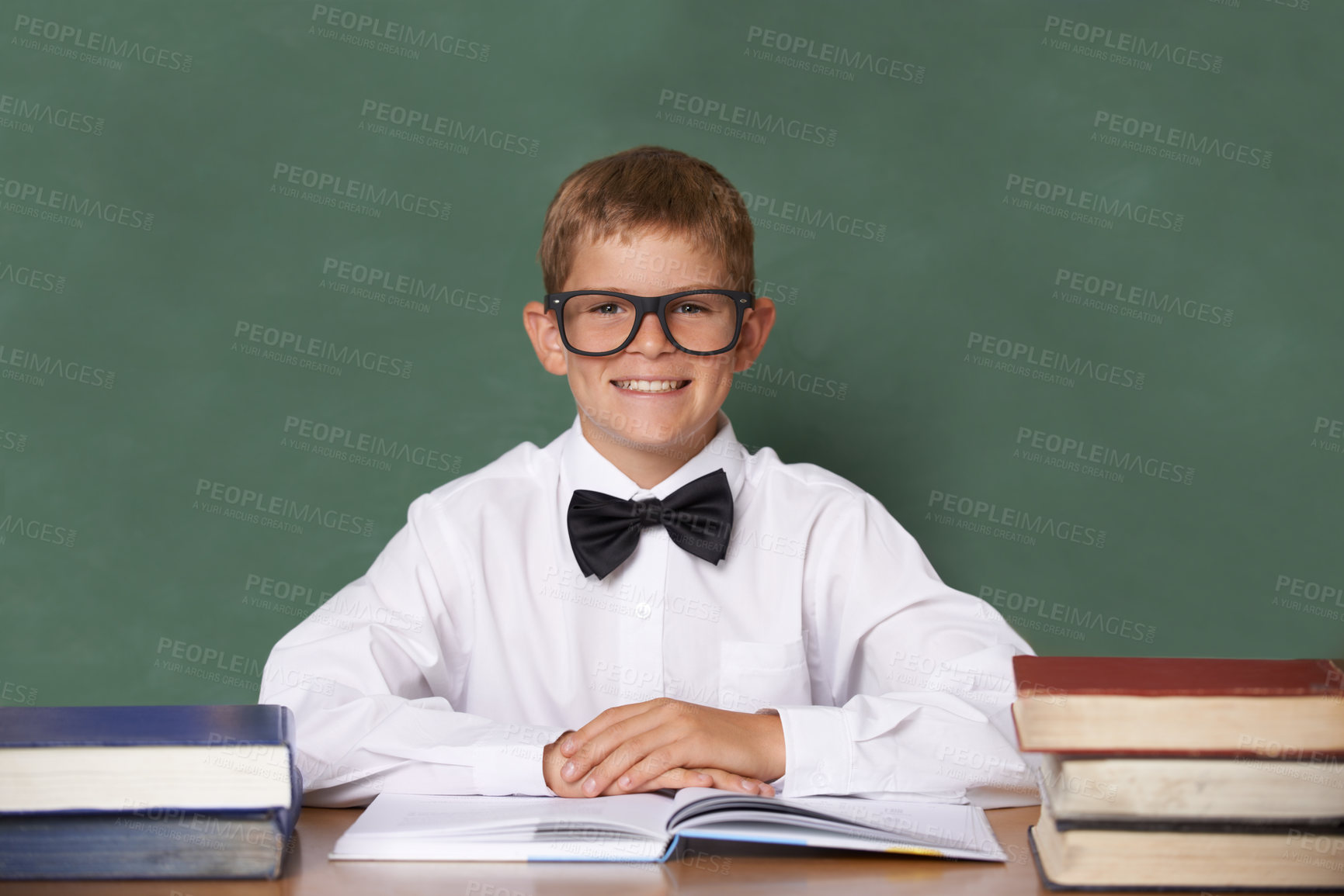 Buy stock photo Boy child, books and school in portrait with smile, information and knowledge with pride in classroom. Student kid, happy and excited for education, learning and development by chalkboard at desk