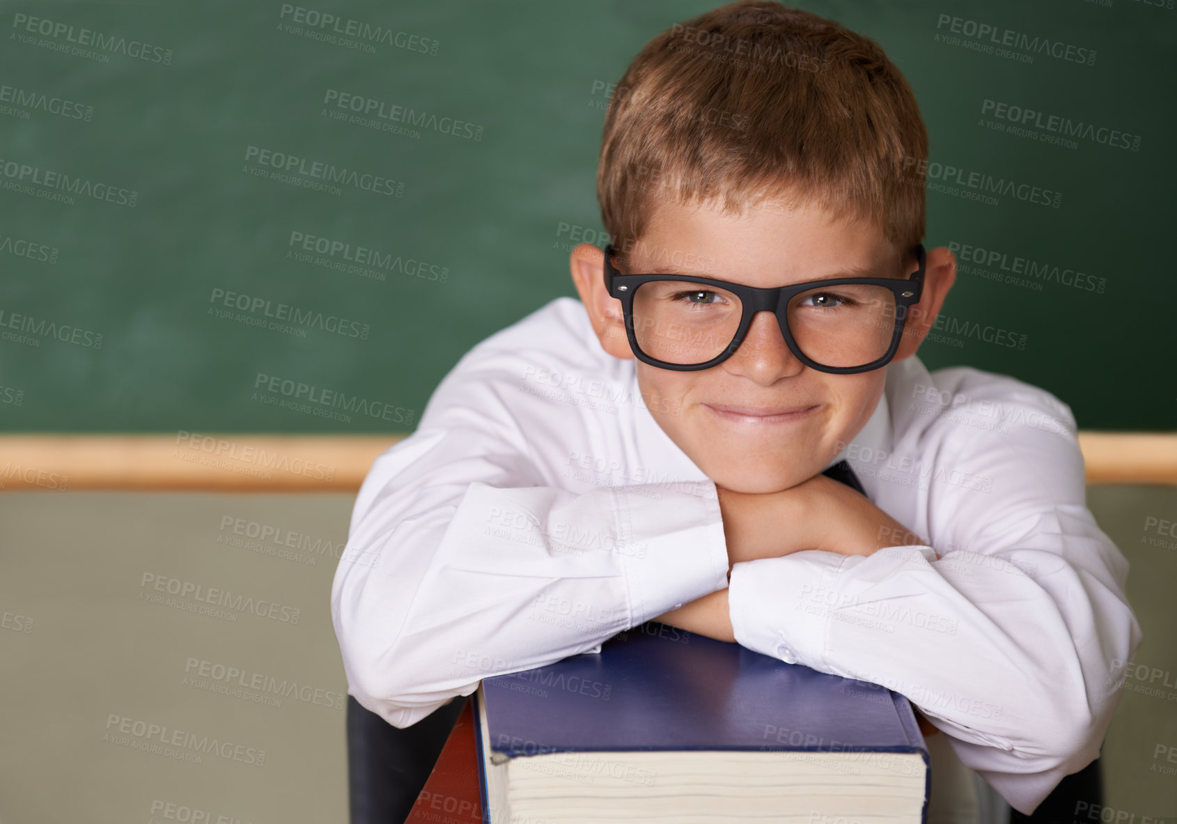 Buy stock photo Happy boy, portrait and relax on books at school for learning, education or knowledge with green chalk board. Face of male person, smart child or young teenager smile for academic literature in class