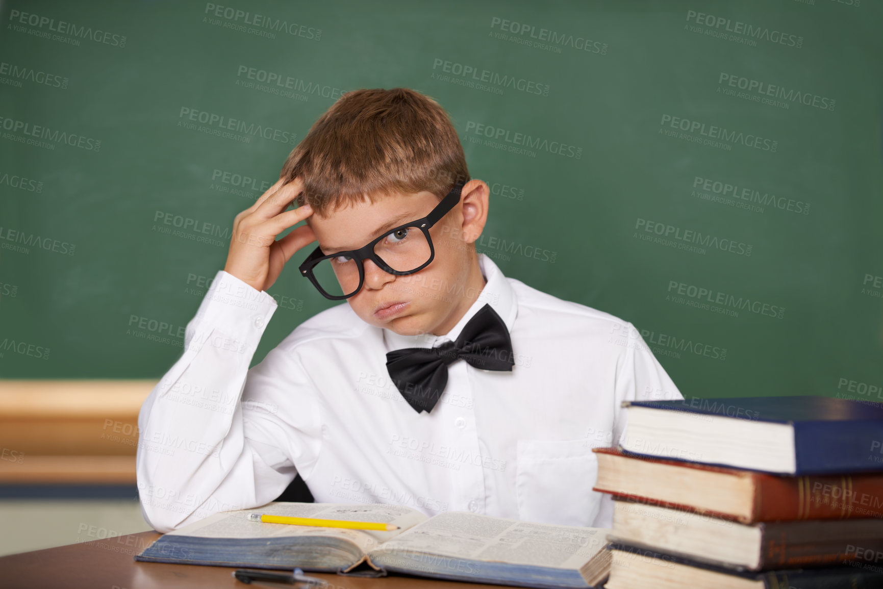 Buy stock photo Student child, stress and portrait with books, classroom and anxiety for exam, assessment and studying for knowledge. Boy kid, notebook and learning for education, development and glasses at table