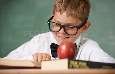 Buy stock photo Happy boy, book and reading at school with apple for learning, education or nutrition by green chalk board. Face of smart child, young kid or teenager smile for academic literature and fruit in class