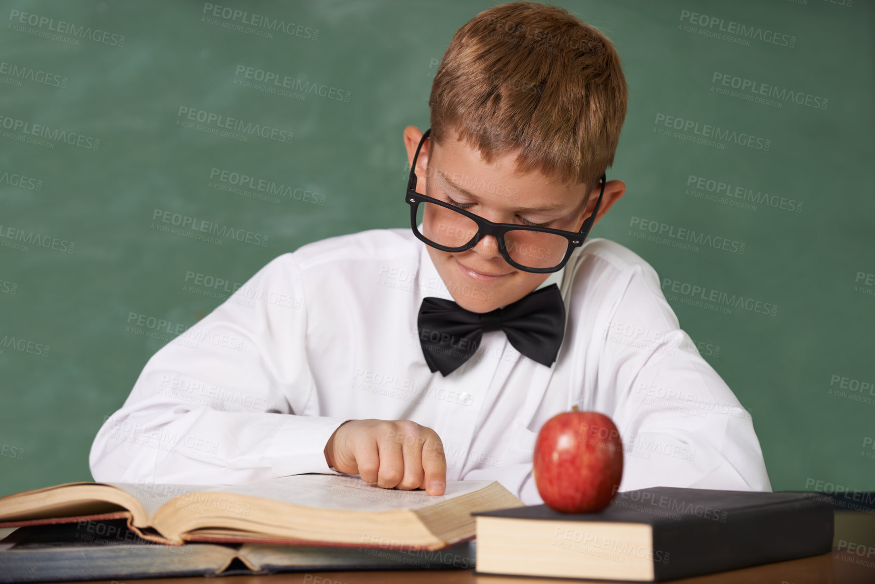 Buy stock photo Young boy, book and reading at school for learning, education or knowledge by green chalk board. Male person, smart child or teenager smile with textbook for academic literature or studying in class