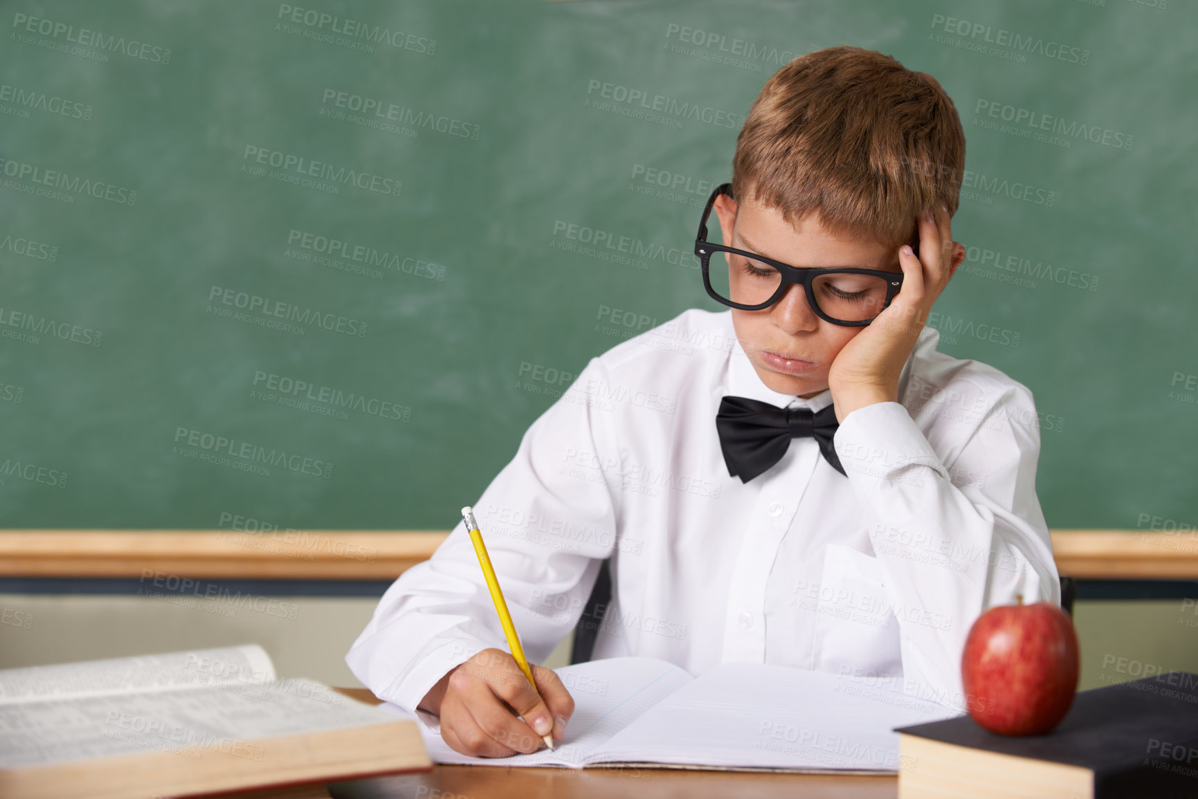 Buy stock photo Frustrated boy child, classroom and writing in books for knowledge, information and studying at academy. Student kid, learning and education with glasses, thinking and stress with dyslexia at school