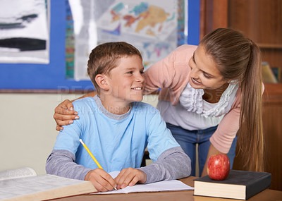 Buy stock photo Happy student, teacher and care in support for education, learning or tutor in classroom at school. Woman, mentor or teaching boy or teen in writing, literature or test for exam or help on class desk
