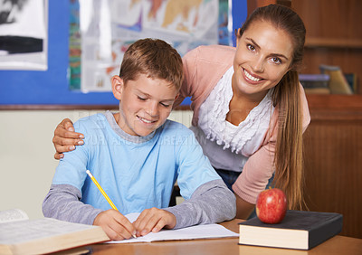 Buy stock photo Happy teacher, student and care in support for education, learning or tutor in classroom at school. Portrait of woman, mentor or teaching boy in writing, literature or test for exam or help in class