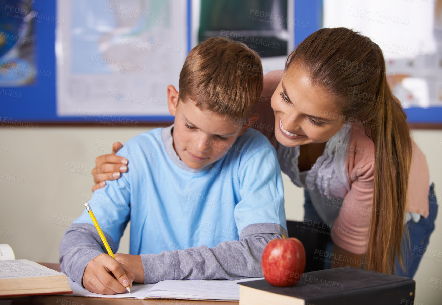 Buy stock photo Happy teacher, support and helping student in education, learning or classroom tutor at school. Woman, mentor or teaching boy in writing, literature or test for book exam, assistance or help in class
