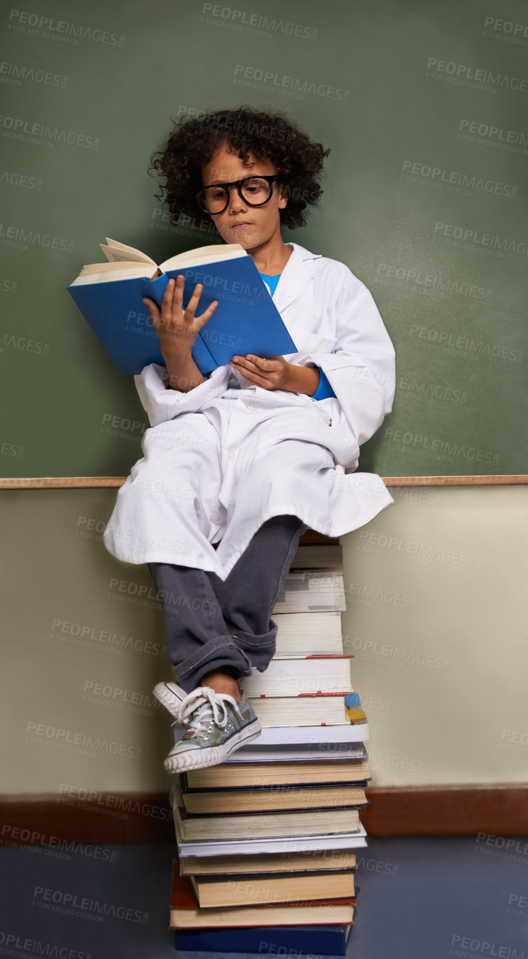 Buy stock photo Child, classroom and reading books for school, science learning and physics knowledge on chalkboard and stack. Smart kid or african student in glasses with library resources and textbook for language