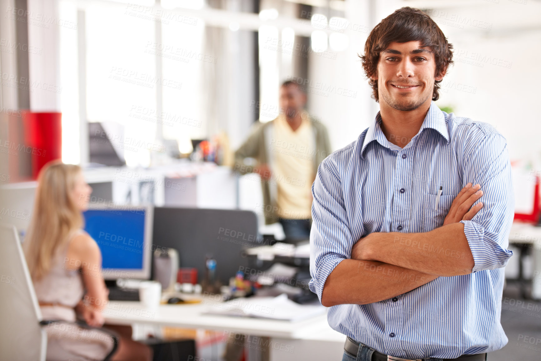 Buy stock photo Shot of a handsome young businessman with his colleagues blurred in the background