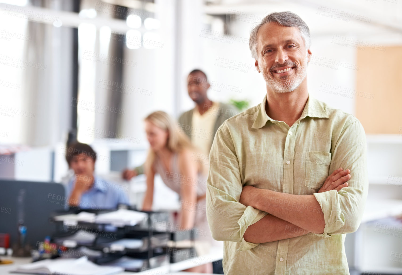 Buy stock photo Shot of a mature businessman with his colleagues blurred in the background