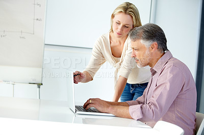 Buy stock photo Shot of two designers working on a laptop together and talking